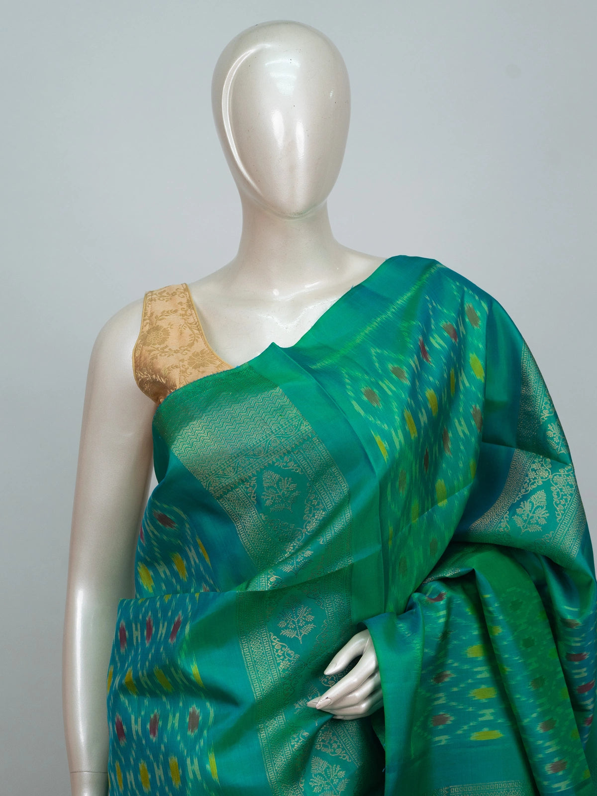 Teal green soft silk saree with ikat motifs, gold zari border and contrast magenta zari pallu