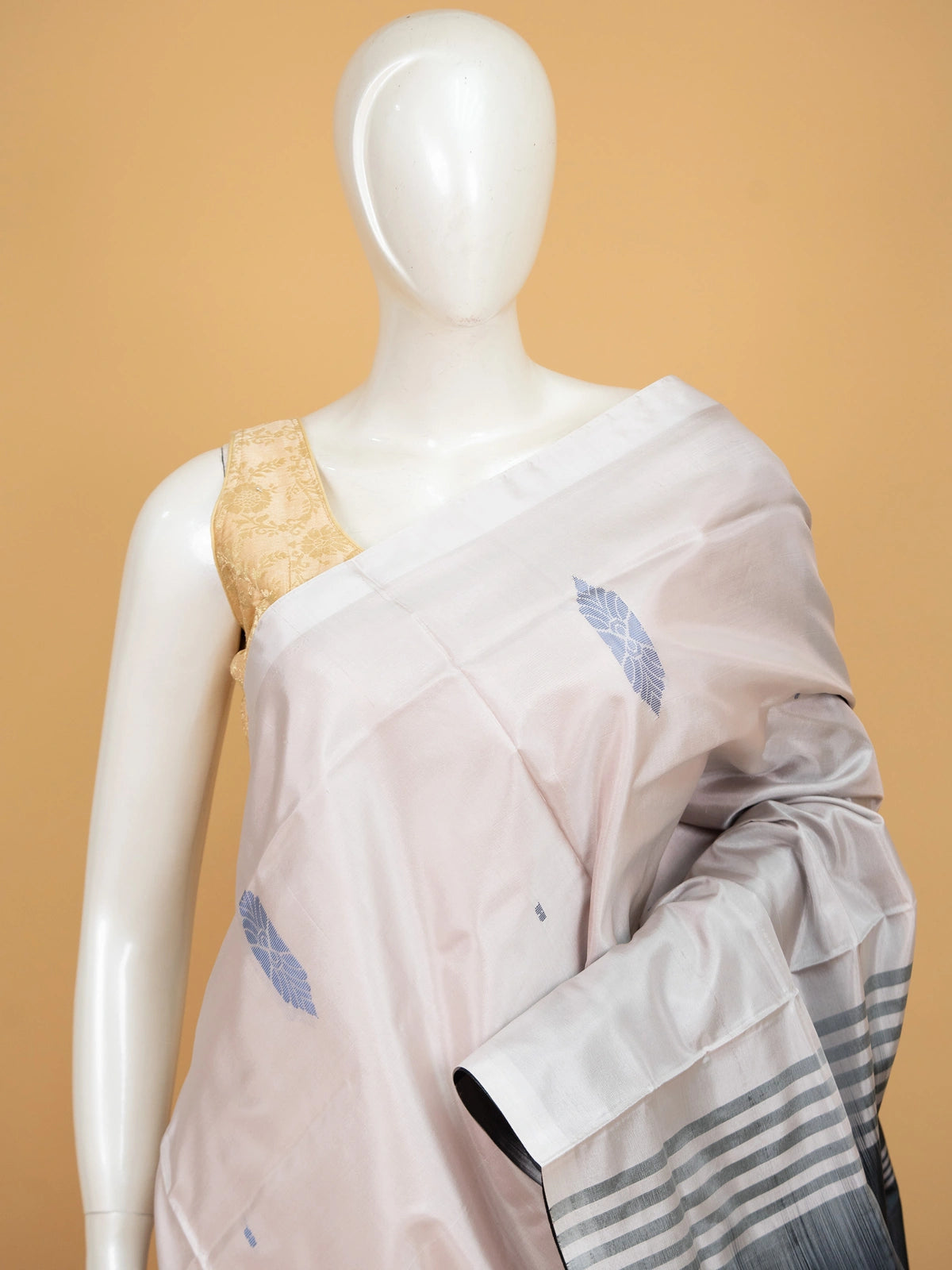 Blush beige Banana Silk saree with charcoal grey contrast pallu, gold zari leaf motifs and blue butta work