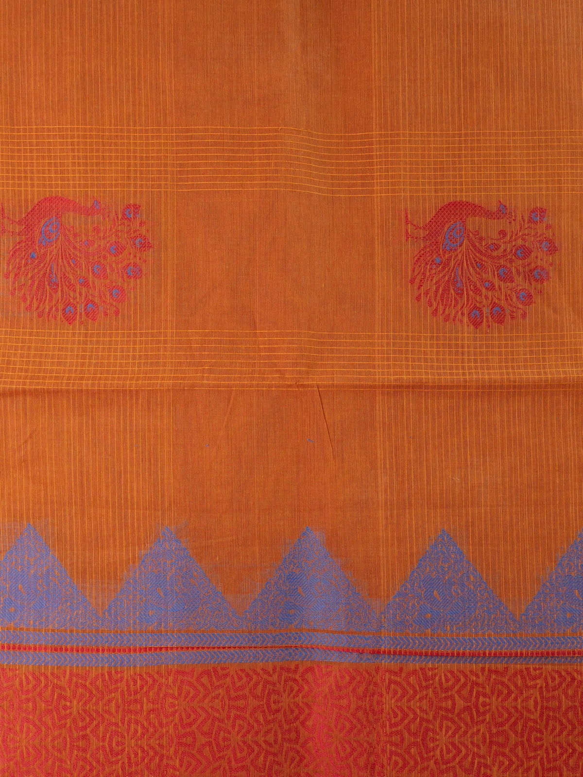 Rust orange silk cotton saree with pink zari border and blue and red peacock motifs