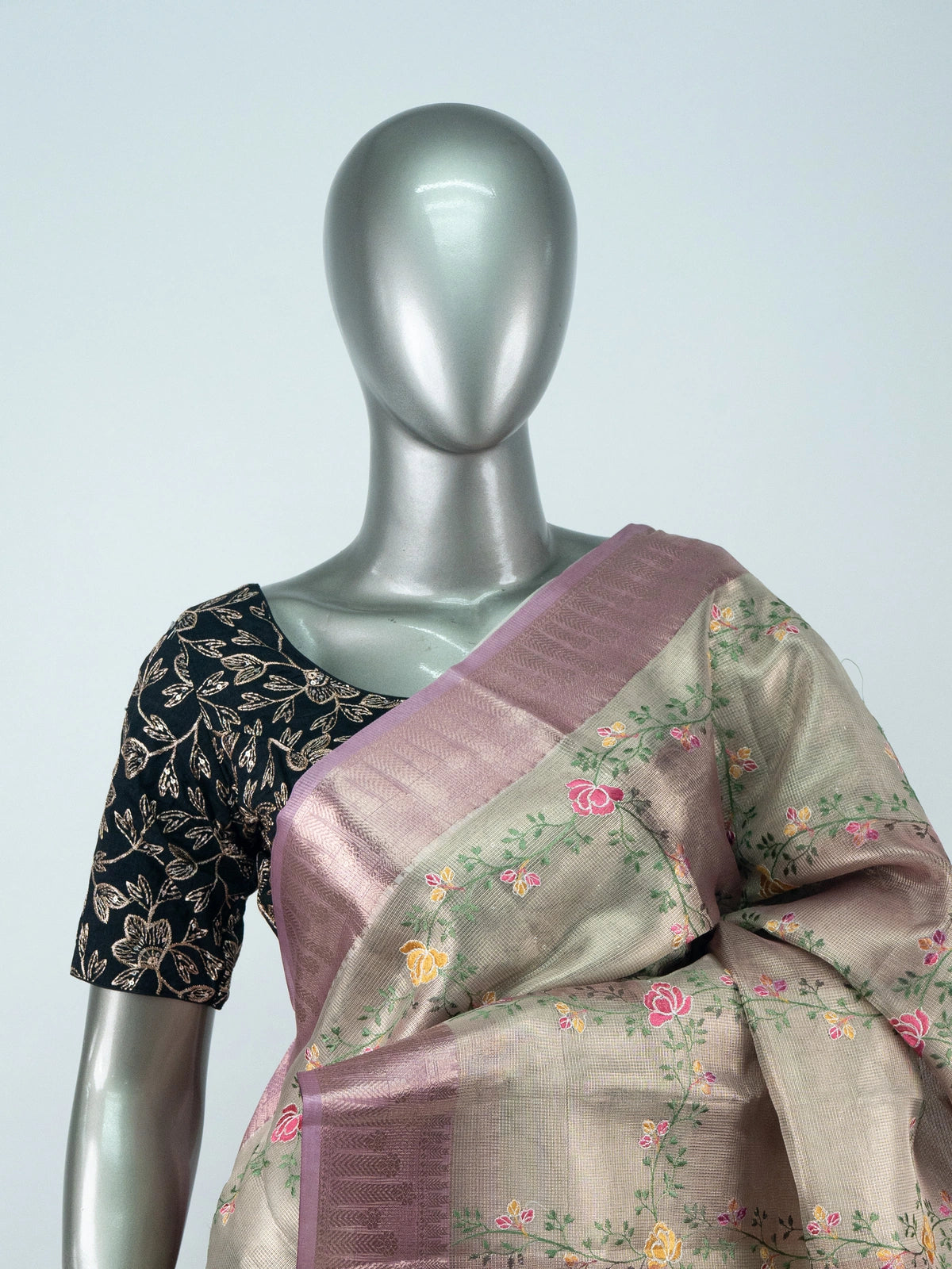 Beige linen cotton saree with mauve pink zari border, multicoloured floral embroidery and a black contrast blouse