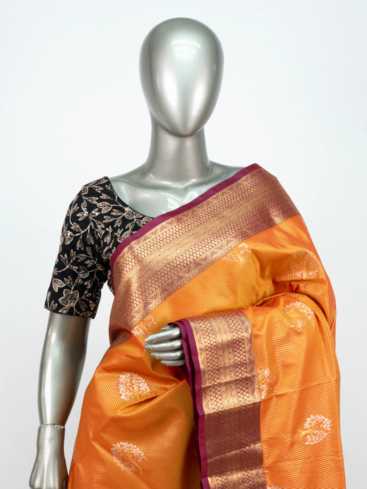 Orange soft silk saree with contrast magenta and gold zari border, woven butta motifs, and black embroidered blouse