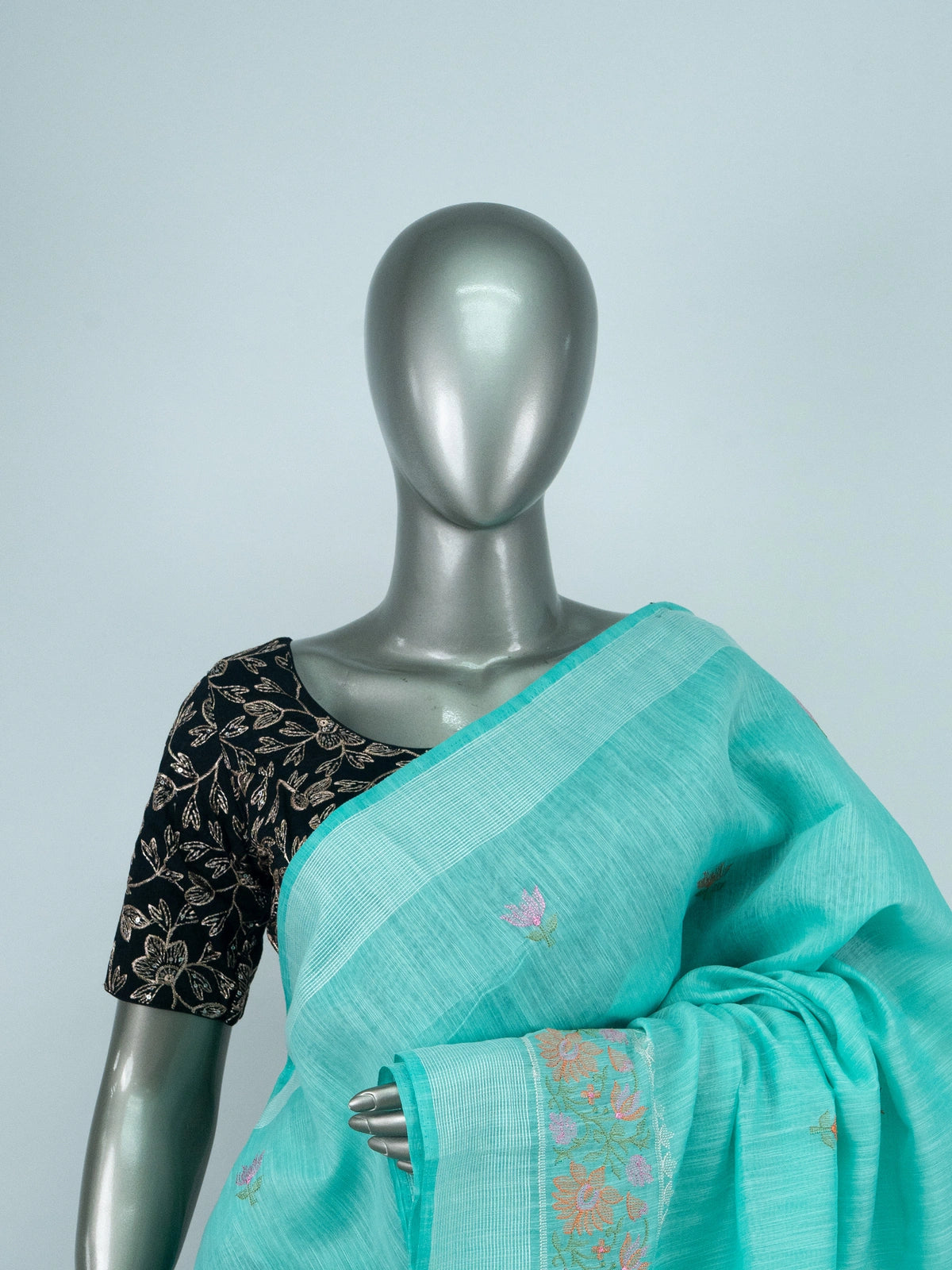 Turquoise linen cotton saree with silver zari border, floral embroidered buta and embroidered pallu, styled with a black blouse