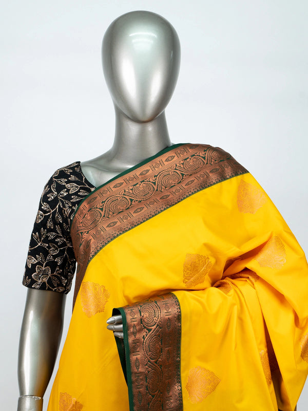 Yellow semi silk saree with dark green contrast border, copper zari buttas and black floral blouse