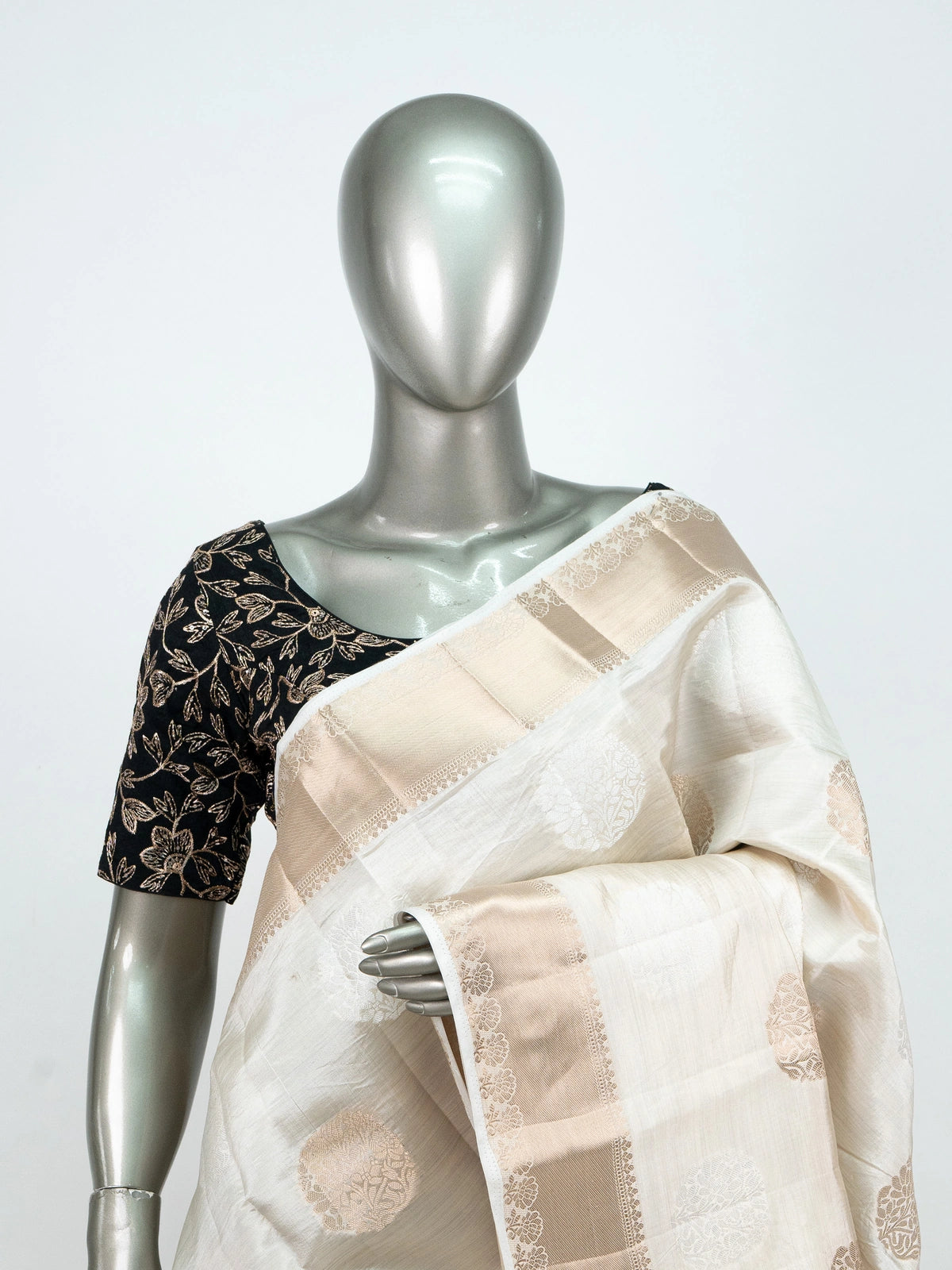 Cream semi raw silk saree with gold zari buttas, gold zari border and contrast black embroidered blouse