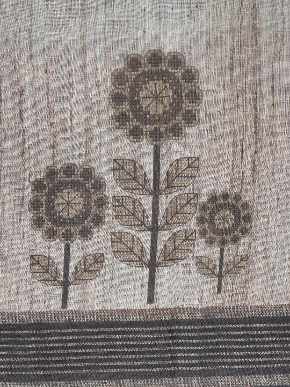 Beige linen cotton saree with grey floral prints and a contrast grey-black striped border