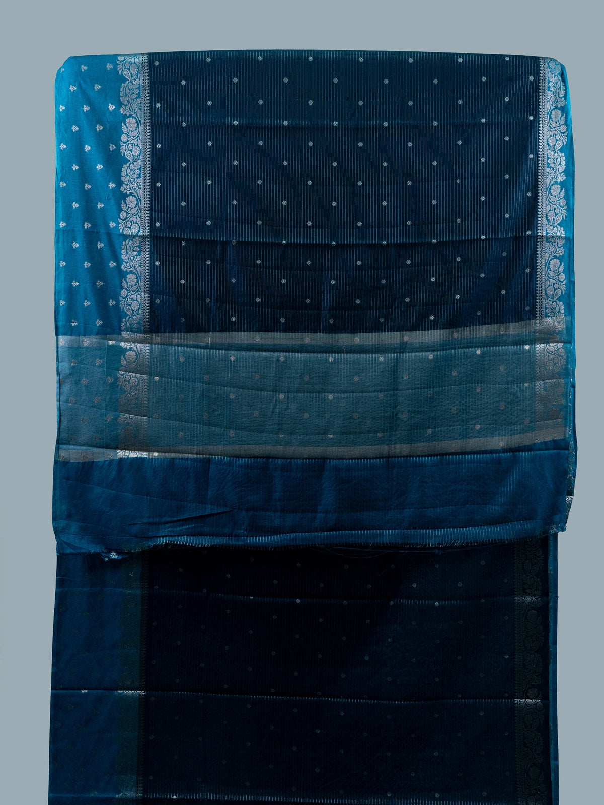 Teal blue semi raw silk saree with silver zari buttis and floral zari border