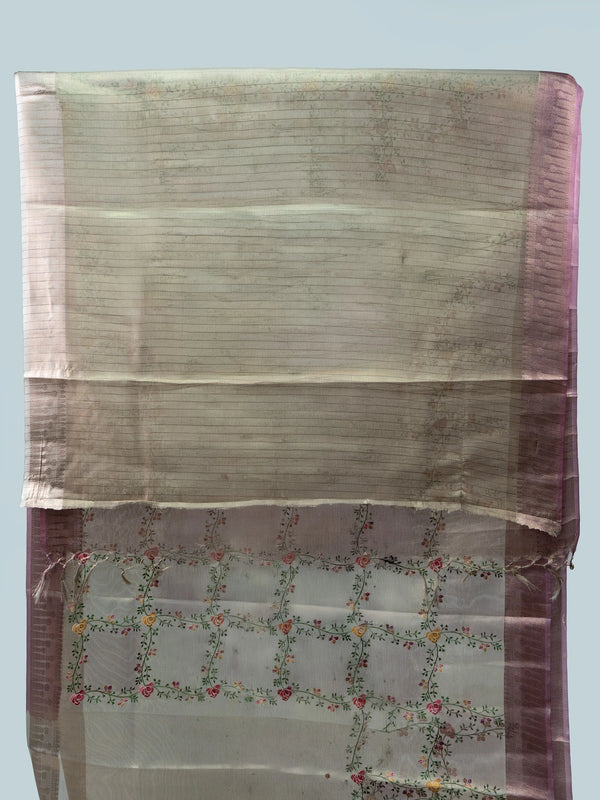 Beige linen cotton saree with mauve pink zari border, multicoloured floral embroidery and a black contrast blouse