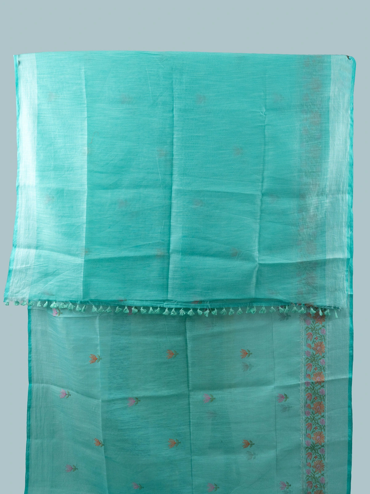 Turquoise linen cotton saree with silver zari border, floral embroidered buta and embroidered pallu, styled with a black blouse