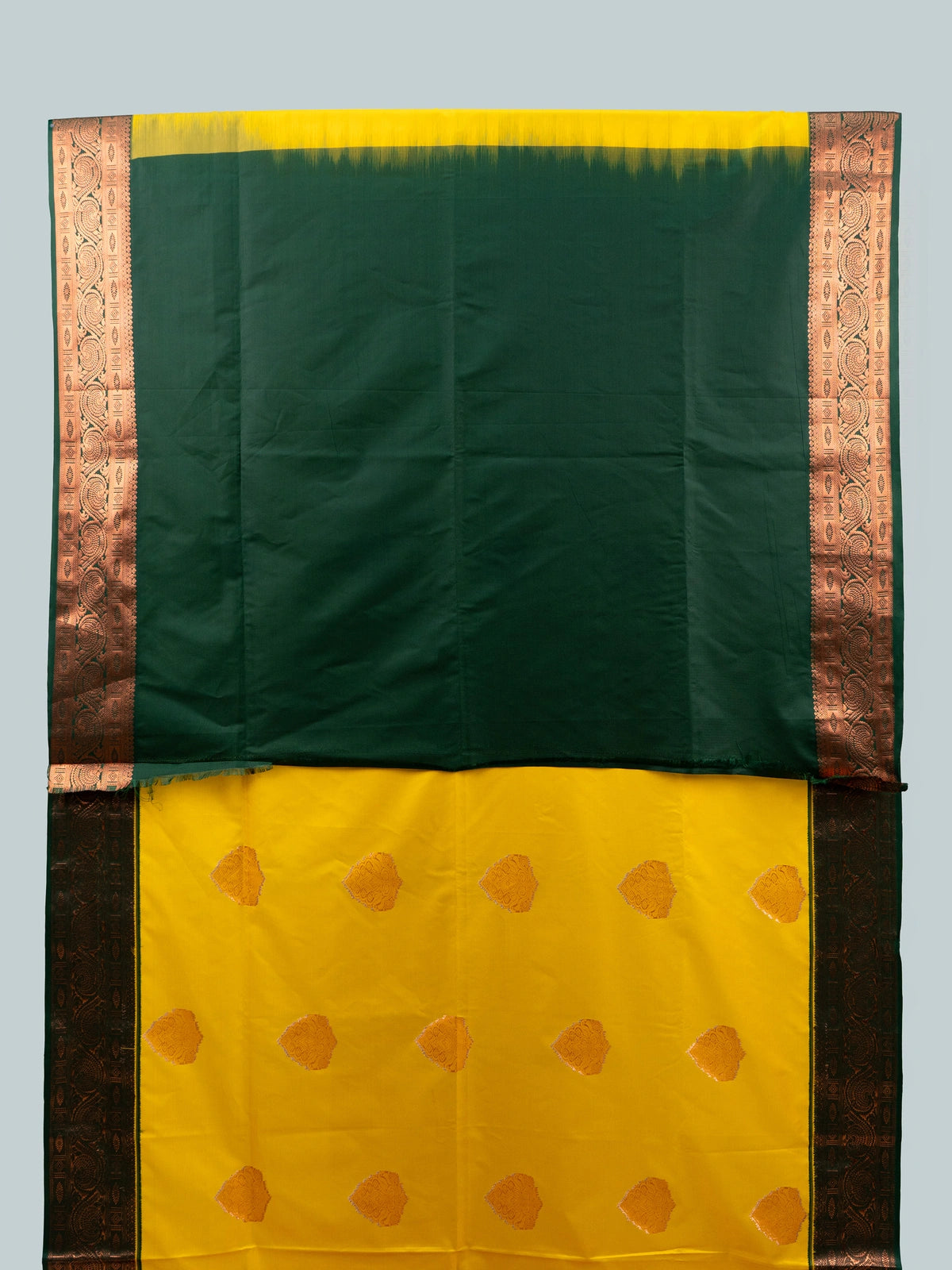 Yellow semi silk saree with dark green contrast border, copper zari buttas and black floral blouse